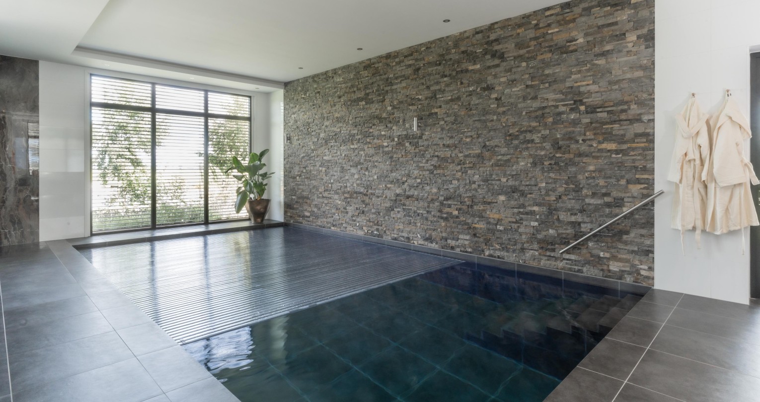 Sfeervol betegeld betonnen binnenbad met wellnessgevoel